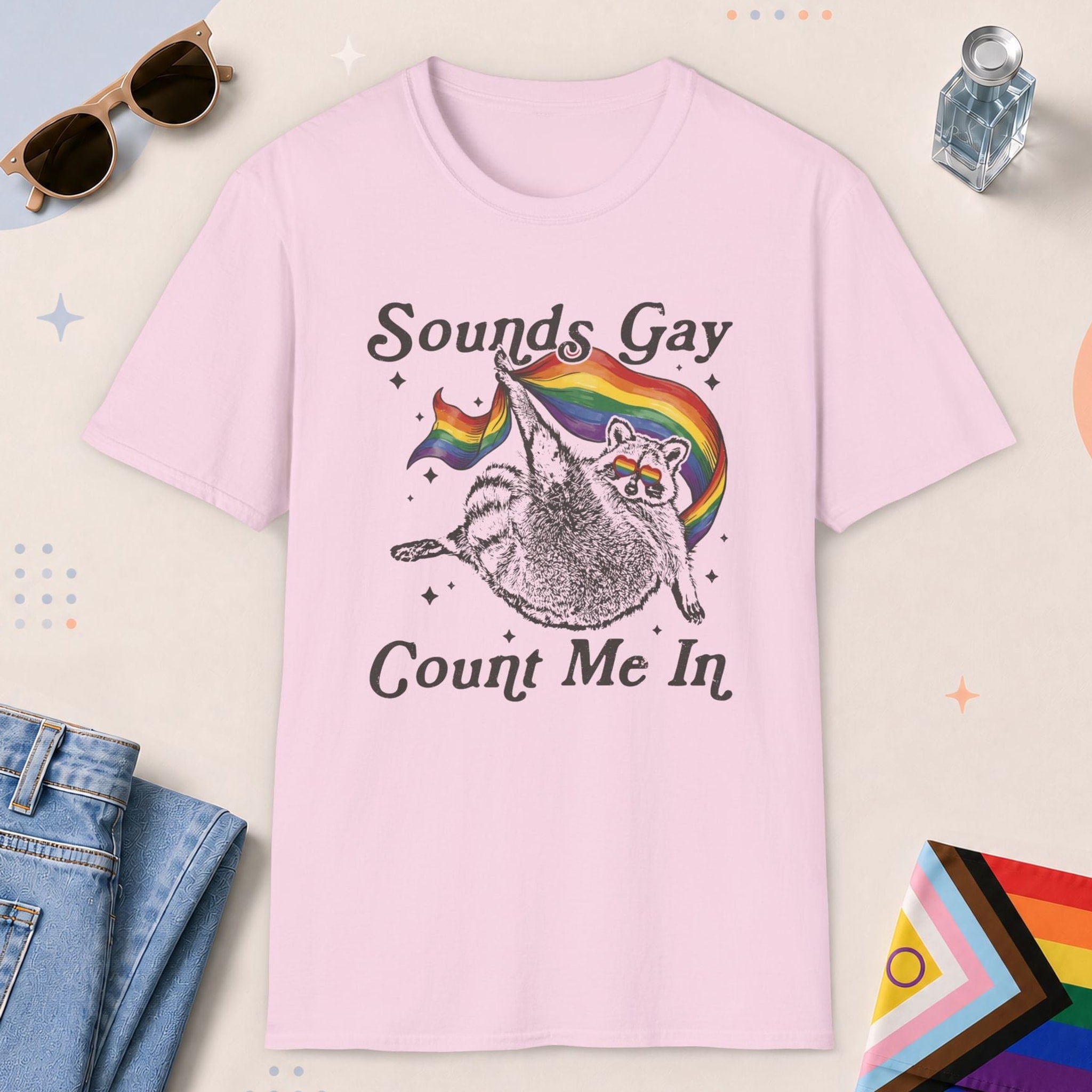 Light Pink color all-gender graphic t-shirt with "Sounds Gay Raccoon" design